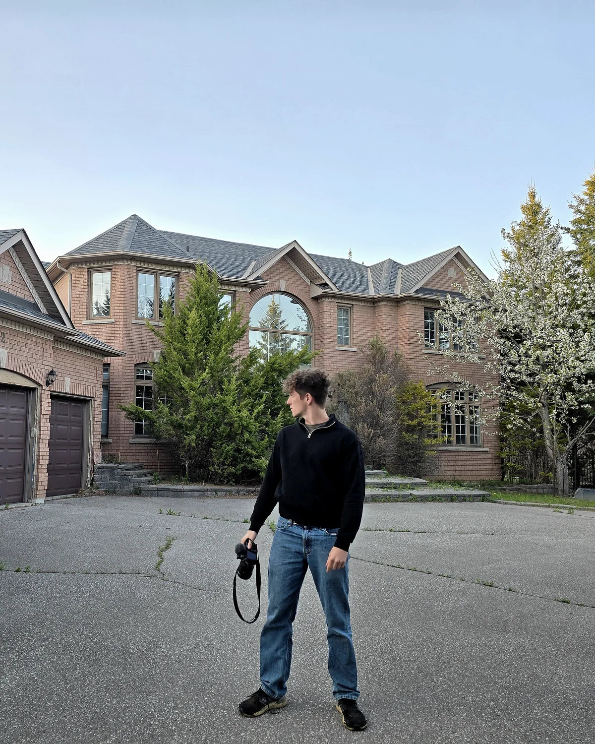 Kaizer holding a camera in front of an abandoned estate